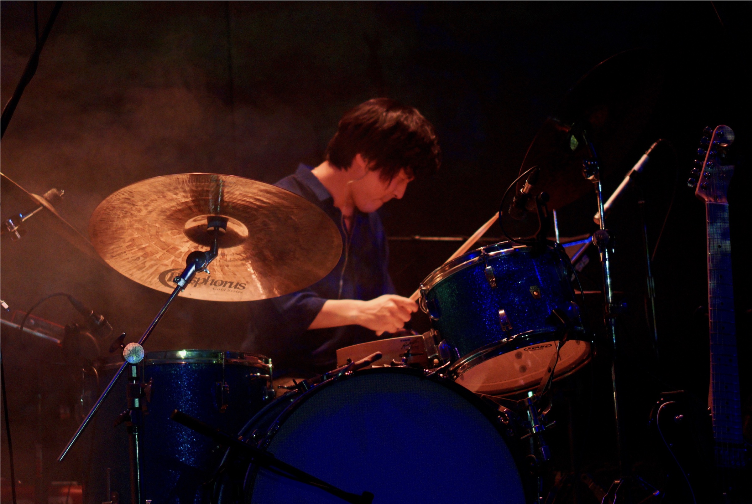 Mir Hwang performing live behind a blue sparkle drum kit